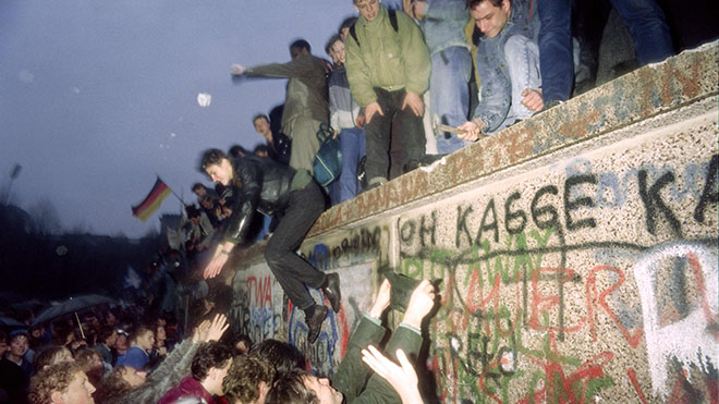 التقطت الصورة في ٢٢ ديسمبر ١٩٨٩ ، يستقبل أشخاص من ألمانيا الشرقية مواطني ألمانيا الغربية عند بوابة براندنبورغ في برلين. سقوط جدار برلين في عام 1989